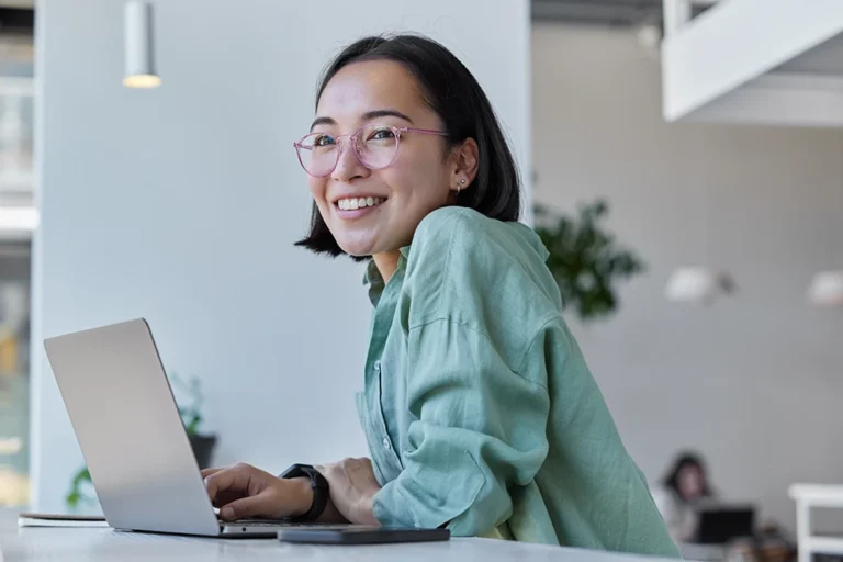 a woman sitting at a desk and working on a laptop